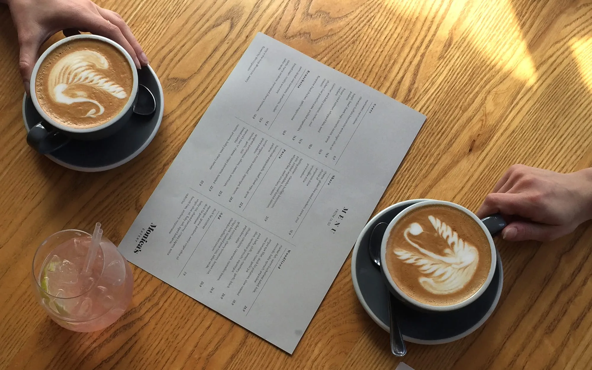 Two flat whites with latte art beside a printed menu